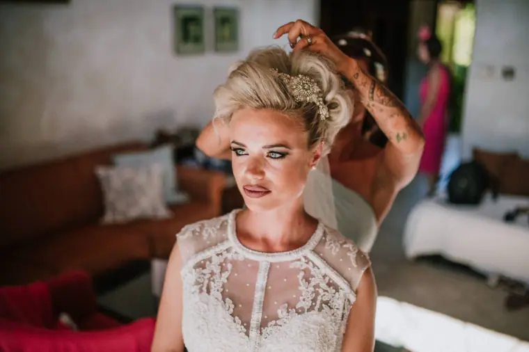 Bride with a lace bodice as a stylist fixes her hair, Elysium, Paphos