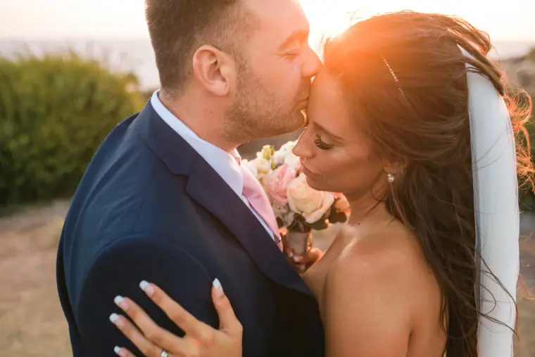 Harry kissing Erica's forehead in warm sunset light at Aphrodite Hills, Paphos