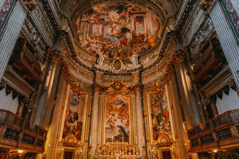 Richly frescoed baroque church interior with gilded altar in Rome