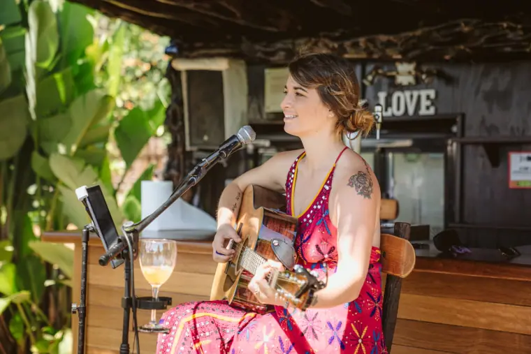 Singer in a pink dress playing guitar for the ceremony, with a LOVE sign behind