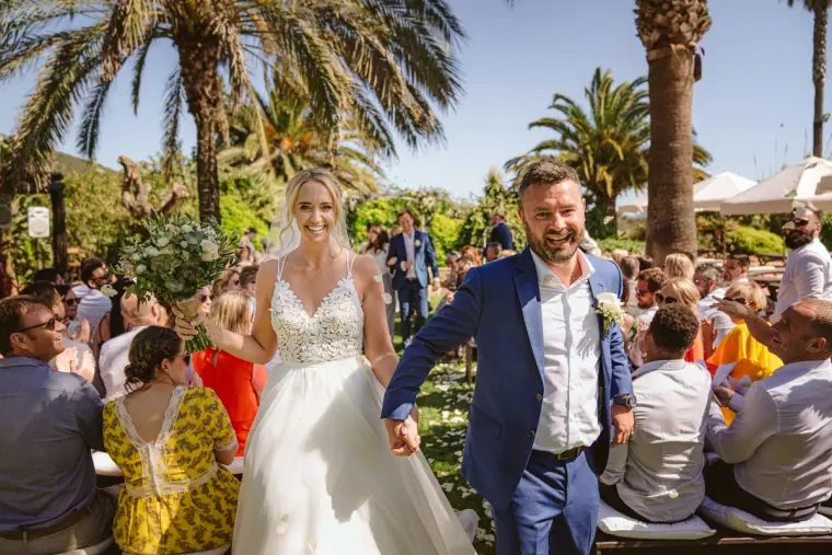 Newlyweds walking back up the aisle smiling as guests applaud