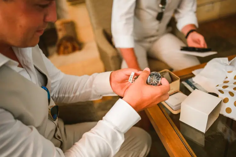 Groom opening a wristwatch gift at a table on the wedding morning