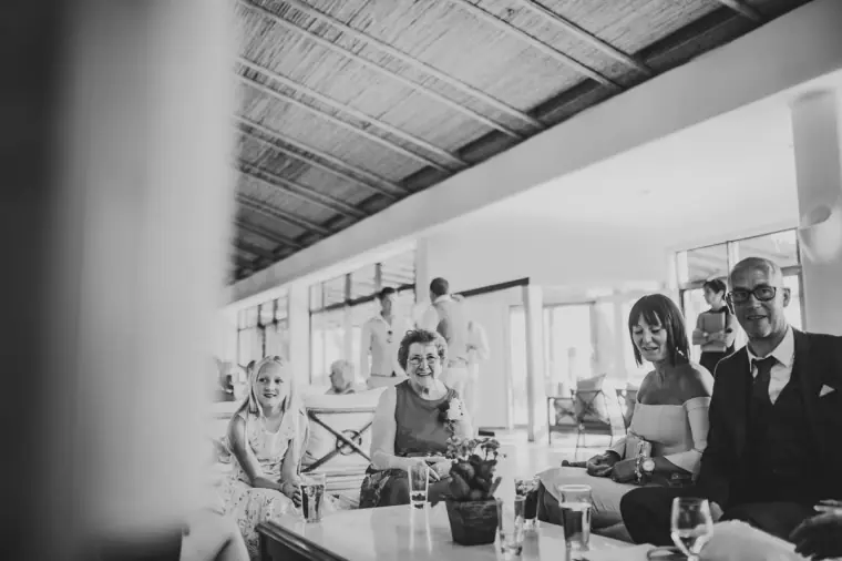 Black-and-white photo of guests chatting at tables in a shaded hotel bar