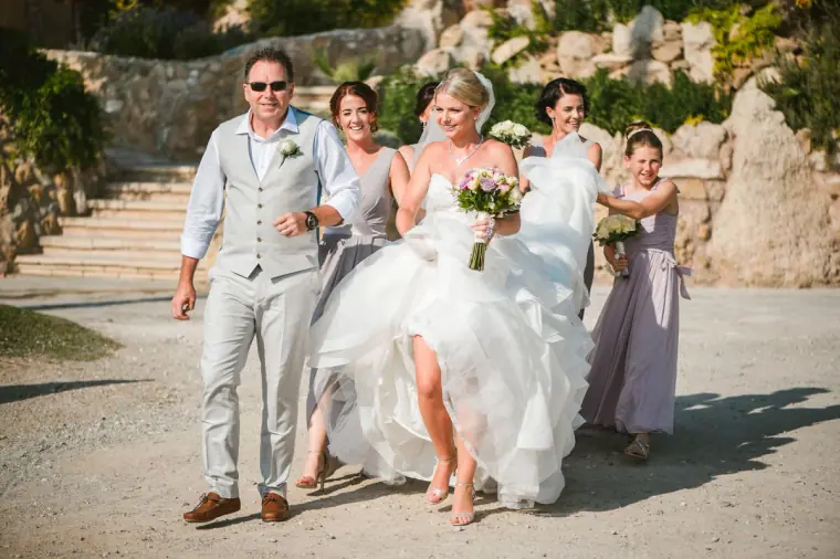 Charlotte walking with her father and bridesmaids down to the seaside ceremony