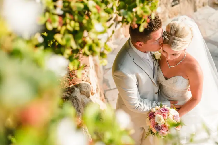 Nathan kissing Charlotte's cheek framed by blooming foliage