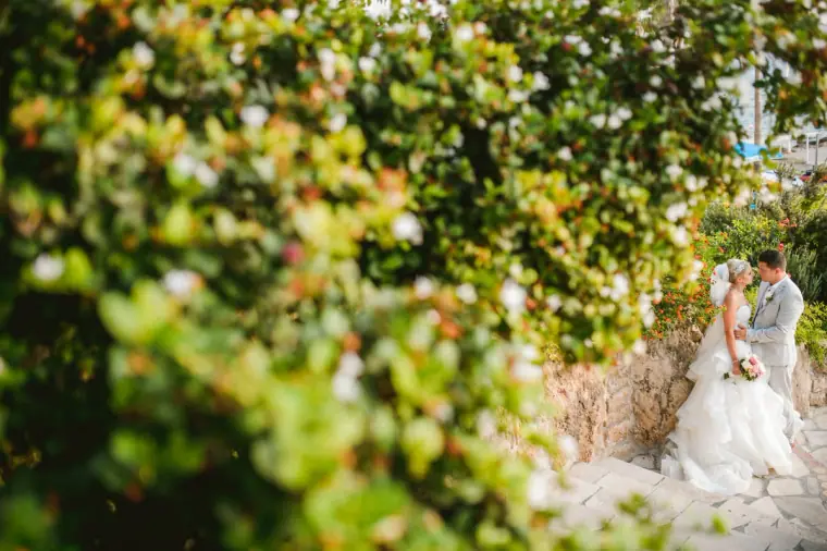 Bride and groom standing in a leafy garden alcove at Coral Beach Hotel