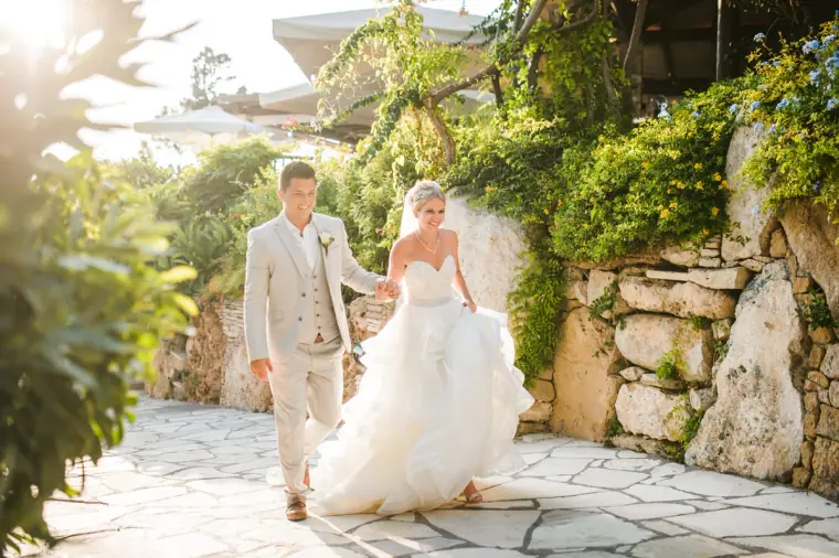 Charlotte and Nathan walking hand in hand along a stone garden path