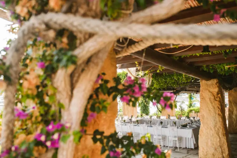 Rope-wrapped pergola with bougainvillea above the long reception tables