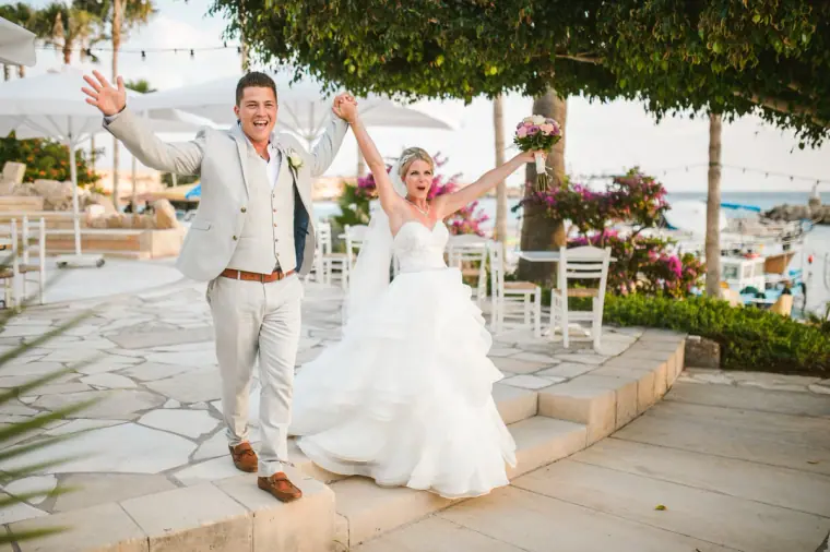 Charlotte and Nathan cheering with arms raised as they enter the reception