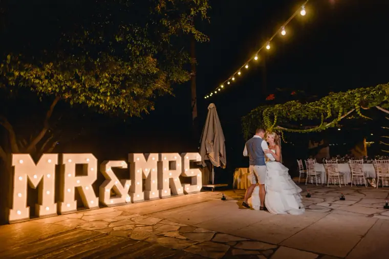 Charlotte and Nathan's first dance beside illuminated Mr & Mrs letters