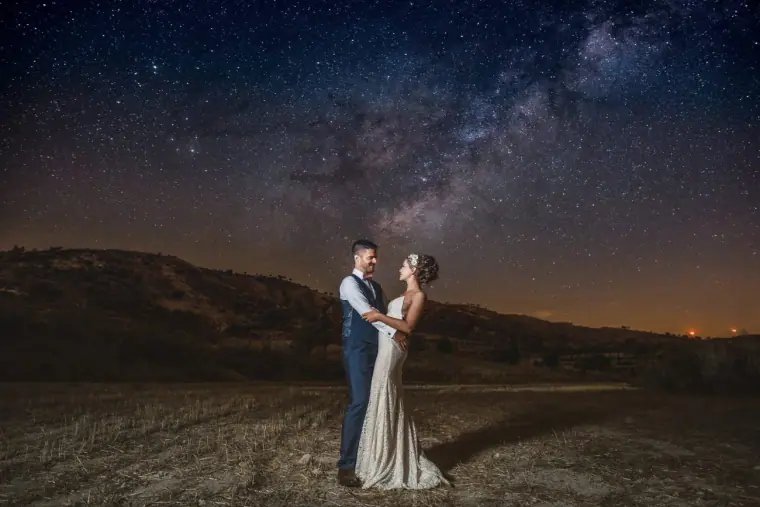 Couple standing under a starry Milky Way sky over the hills at Vasilias Nikoklis Inn, Paphos