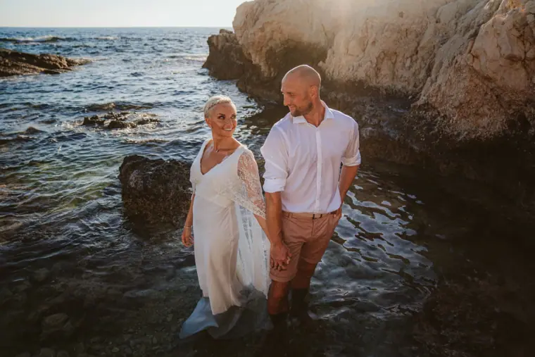 Alana and Luke wading together through the sea between rocks