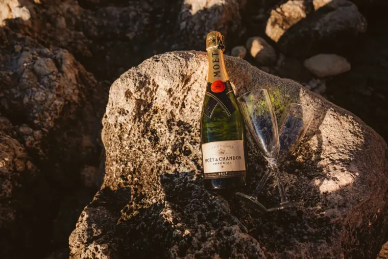 Bottle of Moët champagne resting on a rock with a small bouquet
