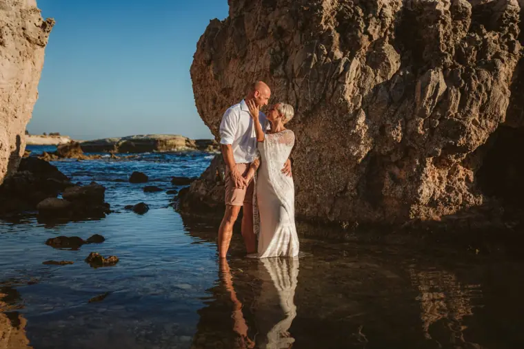 Alana and Luke wading in a rock pool beneath a large boulder
