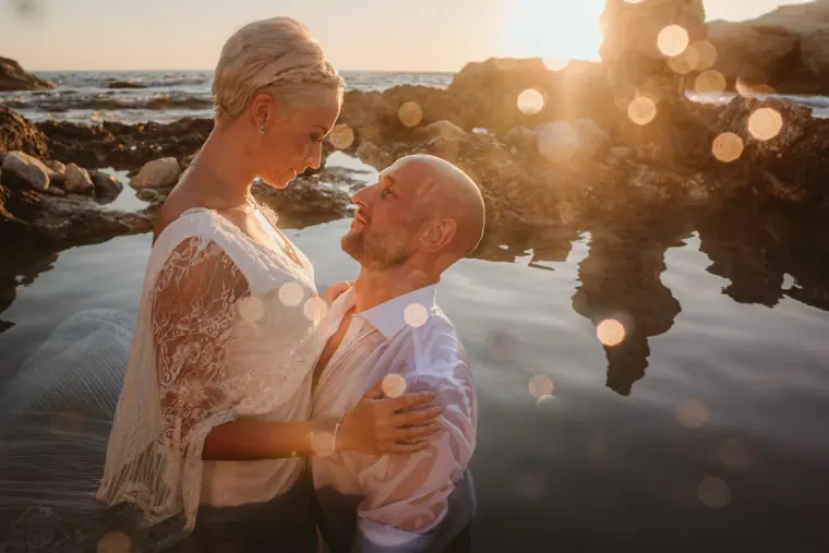 Alana smiling down at Luke as they stand in a rock pool at golden hour