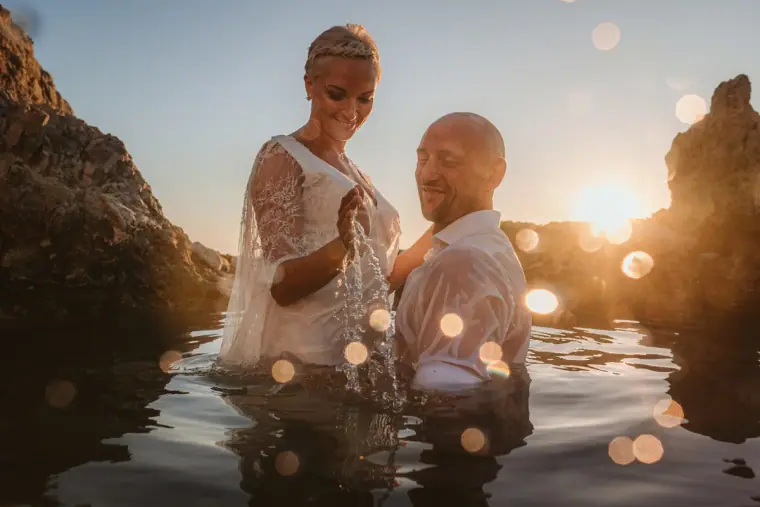 Couple waist-deep in a rock pool, laughing in the late sunlight
