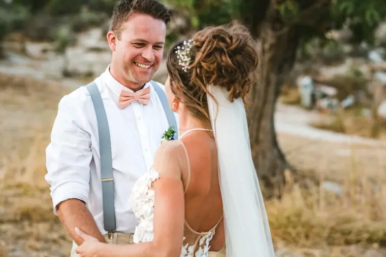 Graeme in braces and a peach bow tie smiling at Amie in her veil