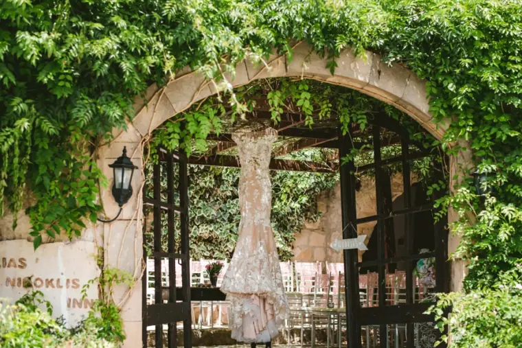 Lace wedding dress hanging in an ivy-covered stone archway at Vasilias Nikoklis Inn, Paphos