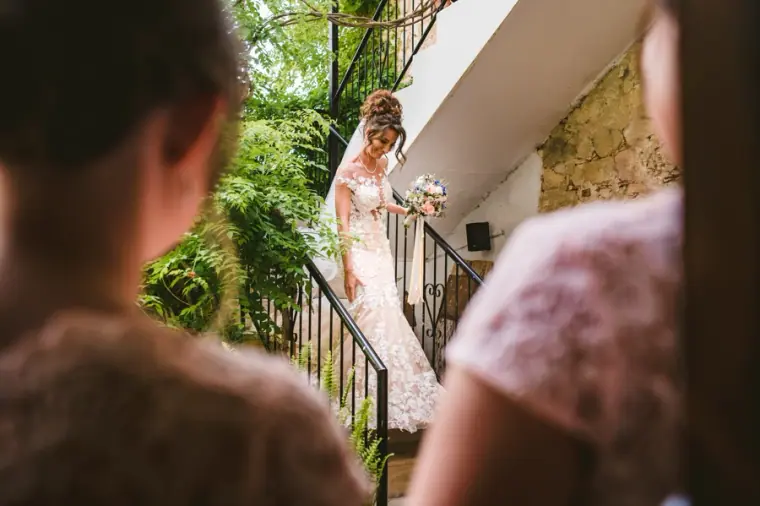 Bridesmaids watching Amie come down the outdoor staircase in her gown