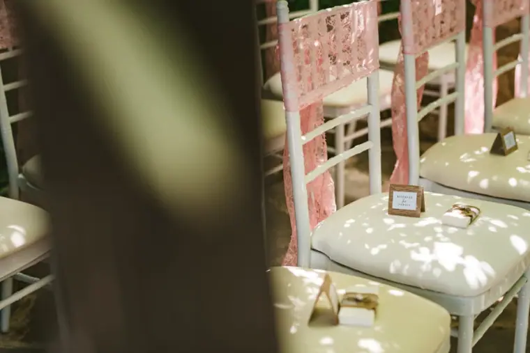 White ceremony chairs with lace backs and a small sign on a seat