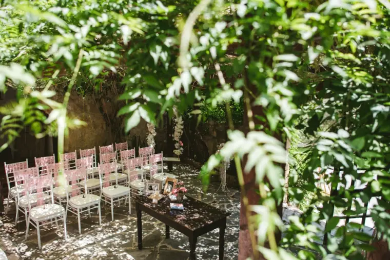 Ceremony chairs set beneath trees in the shaded courtyard at Vasilias Nikoklis Inn, Paphos