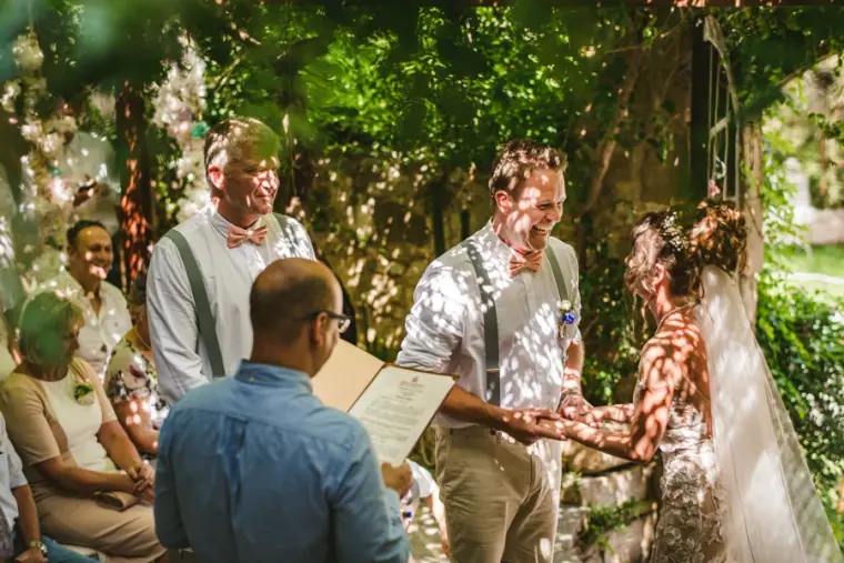 Amie and Graeme holding hands as the celebrant reads during their ceremony