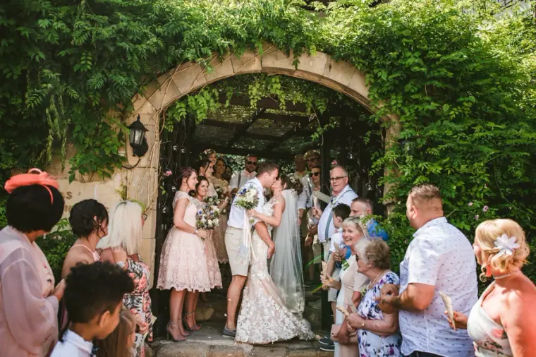 Guests applauding the newlyweds beneath the ivy-covered arch
