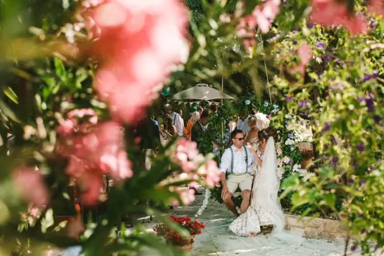 Amie and Graeme seated in the garden, seen through pink blossoms