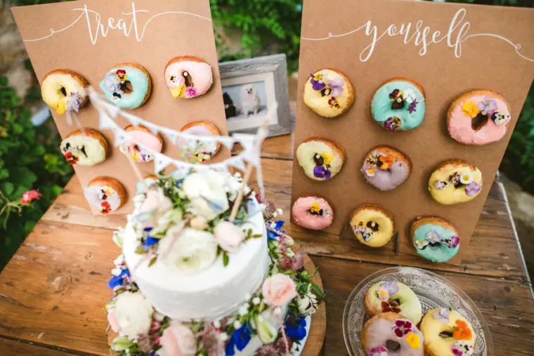 Donut wall reading Treat Yourself beside a floral wedding cake