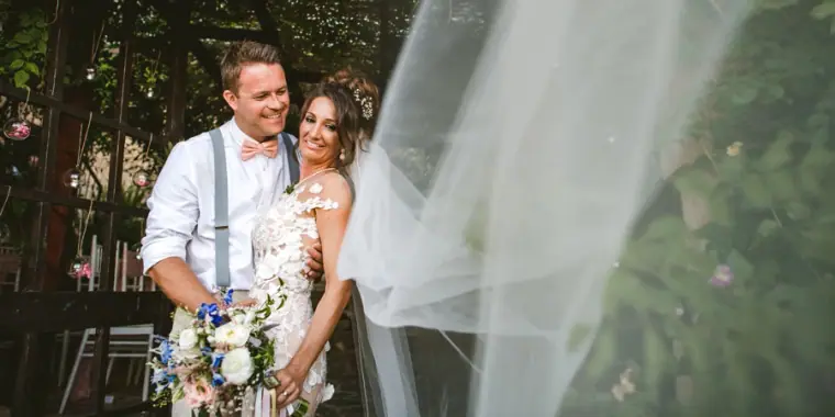 Amie and Graeme laughing together as her veil drifts across the frame