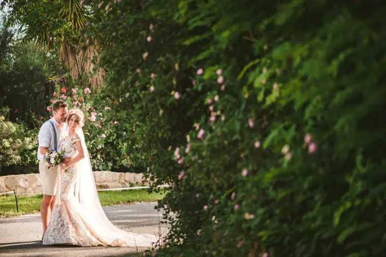 Amie and Graeme by a flowering hedge in the gardens of Vasilias Nikoklis Inn