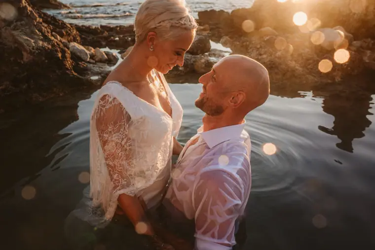 Alana and Luke standing in a sunlit rock pool, smiling at each other