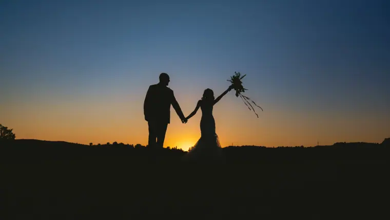 Emily and Chris silhouetted at sunset, the bride raising her bouquet, at Minthis, Paphos
