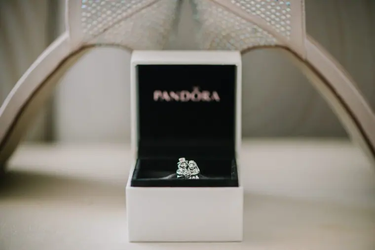Open Pandora box holding a charm, on a white surface