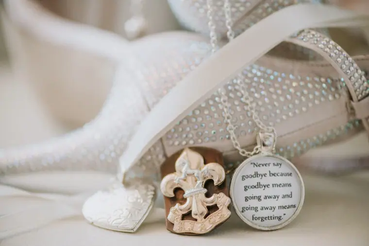 Sparkly bridal shoes beside a fleur-de-lis charm and a quote medallion