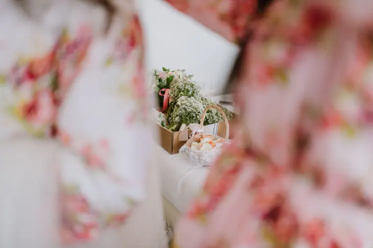 Bridesmaids in floral robes beside a box of bouquets, softly out of focus