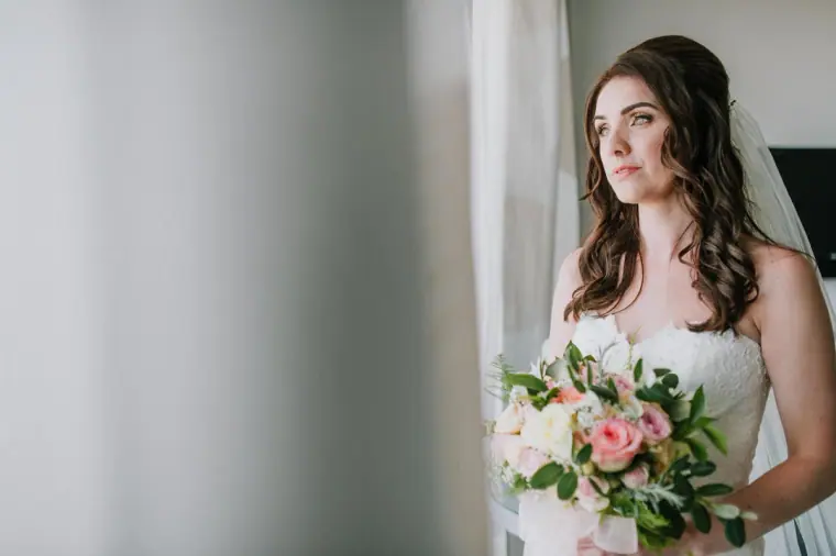 Claire gazing out of the window holding her pastel bouquet