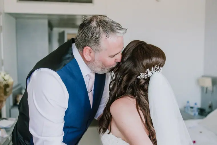 Claire's father kissing her forehead as she gets ready