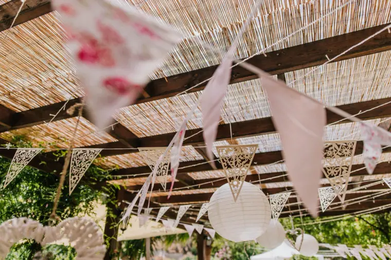Floral fabric bunting and paper lanterns hanging from a reed pergola