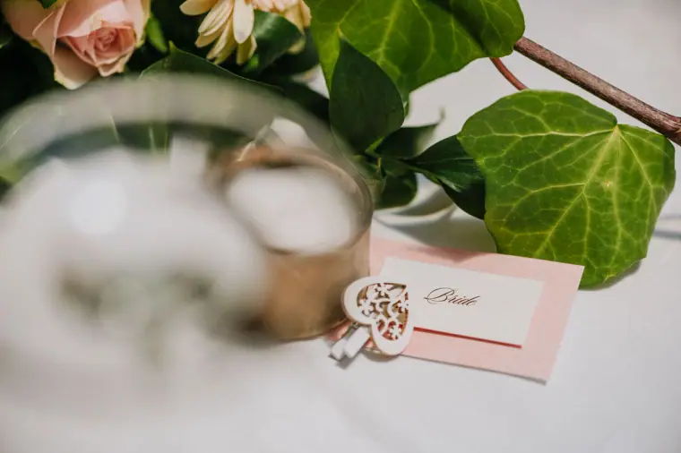 Bride's place card and wooden heart beside roses and ivy on the top table