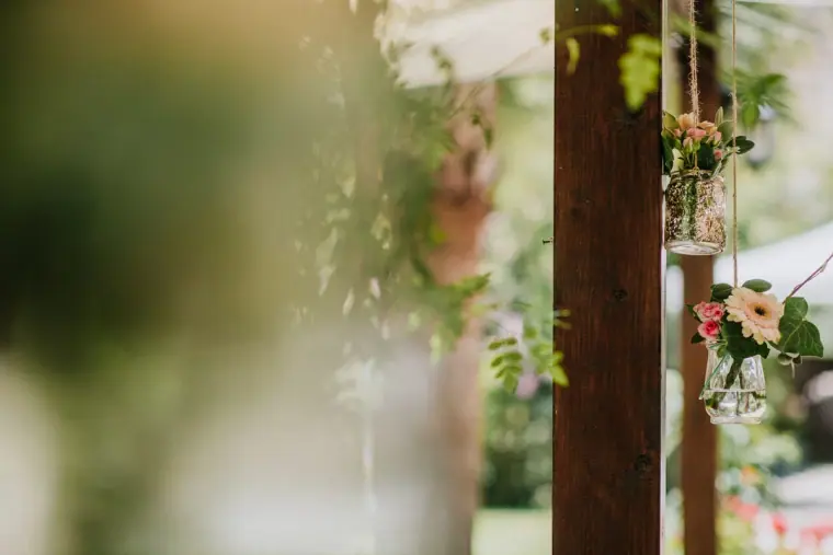 Hanging jar of flowers in a leafy courtyard, softly out of focus