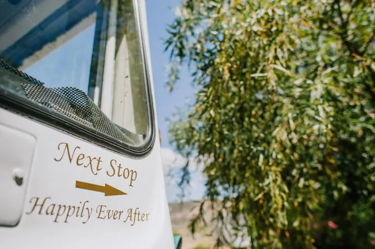 Vintage wedding bus with Next Stop Happily Ever After lettering on the door