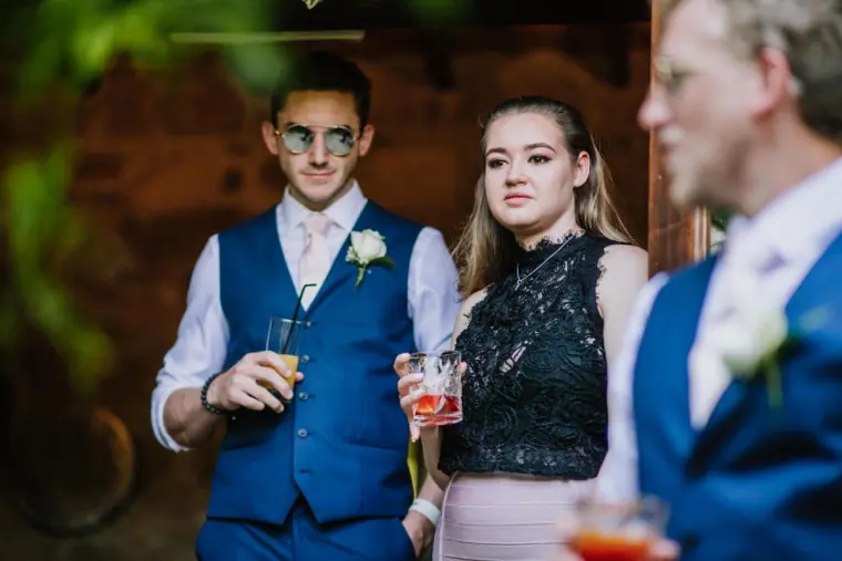 Groomsmen in navy waistcoats chatting with a guest at the drinks reception