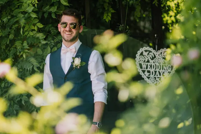 Sean smiling in a navy waistcoat beside a hanging Wedding Day heart sign