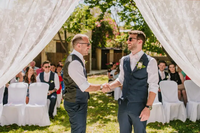 Sean shaking hands with a guest beneath the lace ceremony arch