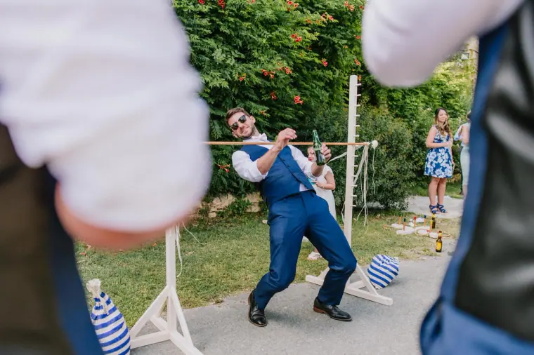 Groomsman playing a garden game on the lawn as guests watch
