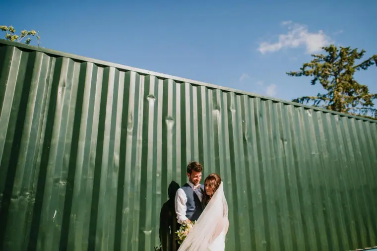 Claire and Sean against a bright green corrugated wall under a blue sky