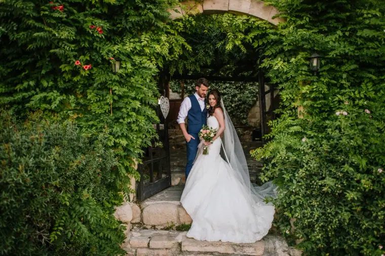 Newlyweds under the ivy-covered stone arch at Vasilias Nikoklis Inn, Paphos