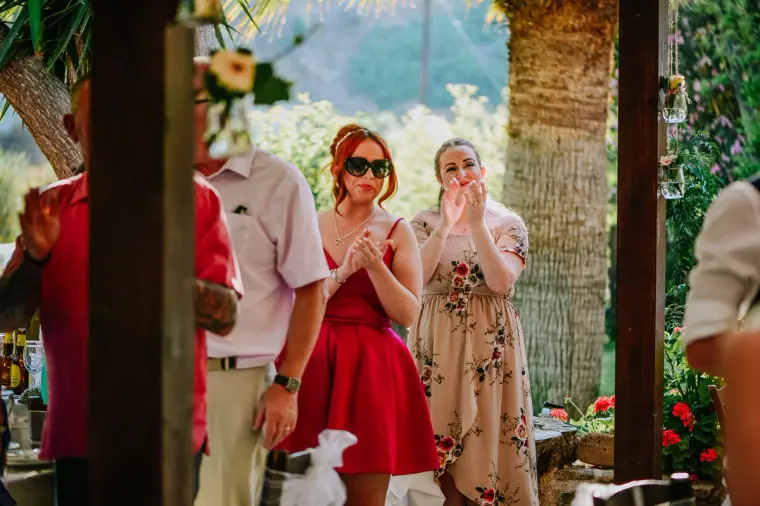 Guests in sunglasses smiling and applauding at the reception