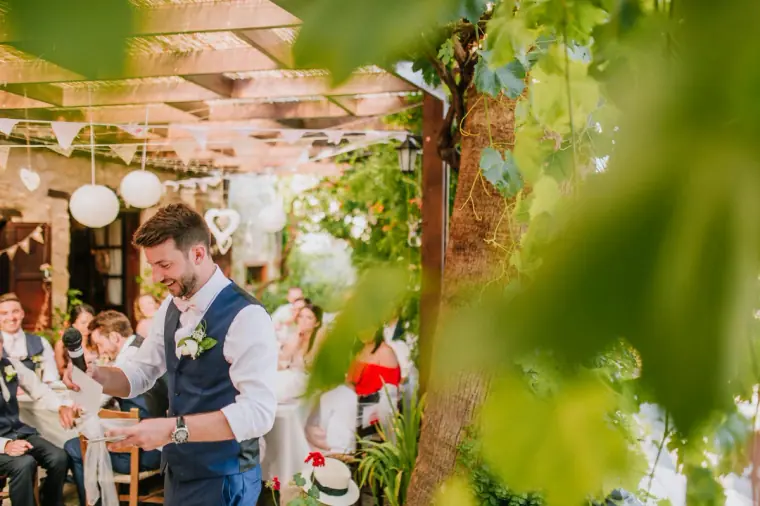 Groomsman reading his speech under the pergola, framed by leaves